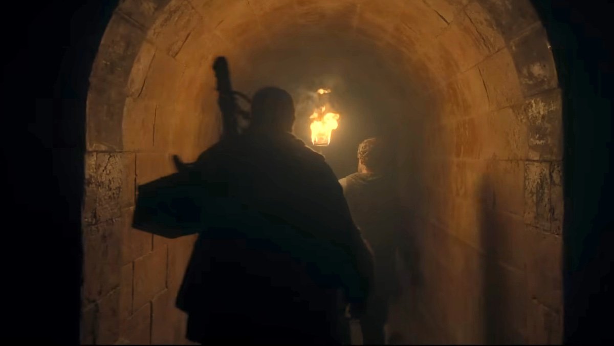 Two men with torches and rat traps walk through a tunnel on House of the Dragon