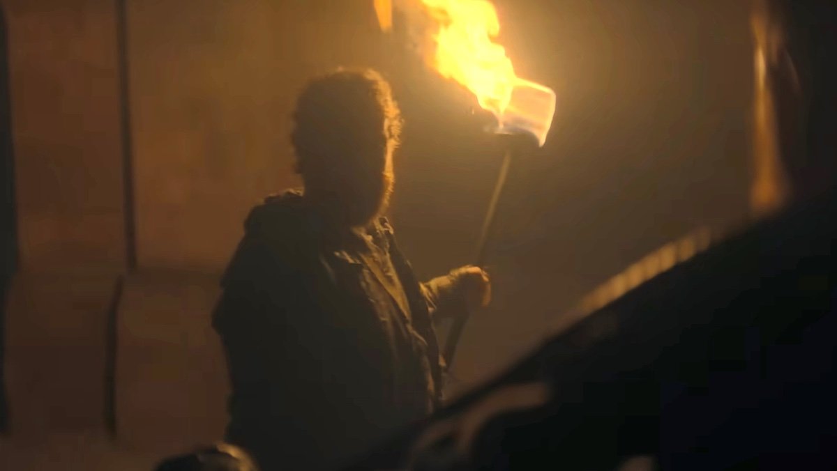 A bearded man holds a torch at night on House of the Dragon