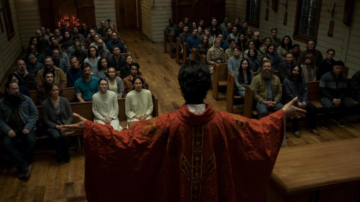 A still from Midnight Mass shows Father Paul speaking to his parishioners in church 