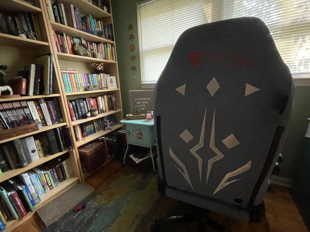 The back of the Secretlab TITAN Evo gaming chair with a blue Ahsoka Tano SKINS cover sitting in front of a desk and bookshelf